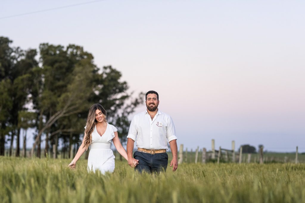 Casal caminhando no capim alto do campo ao entardecer