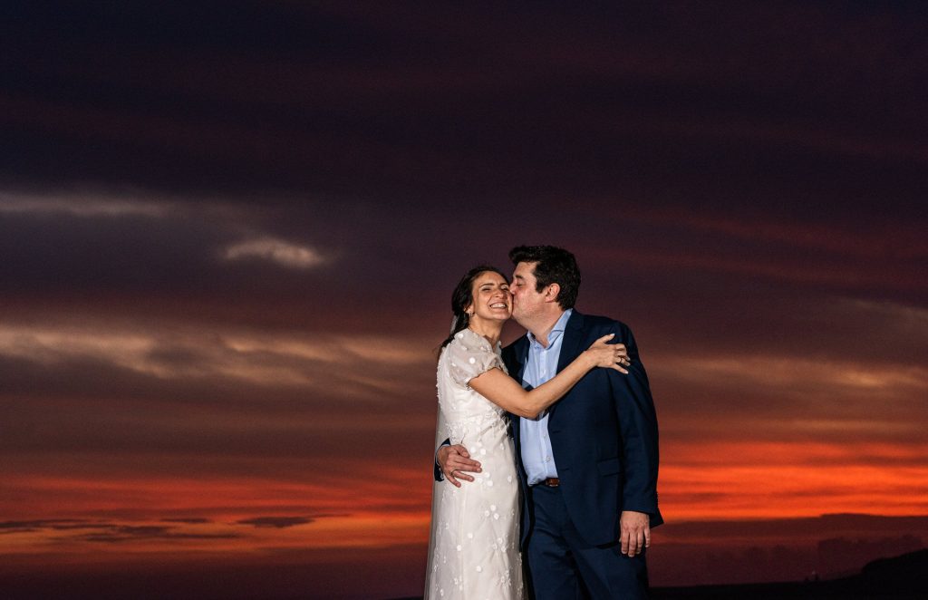 A couple embracing in front of a red sunset over the sea in Punta del Este