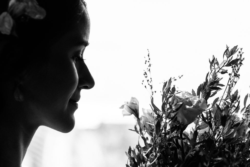 Perfil de la novia a contraluz junto a un ramo de flores, en blanco y negro