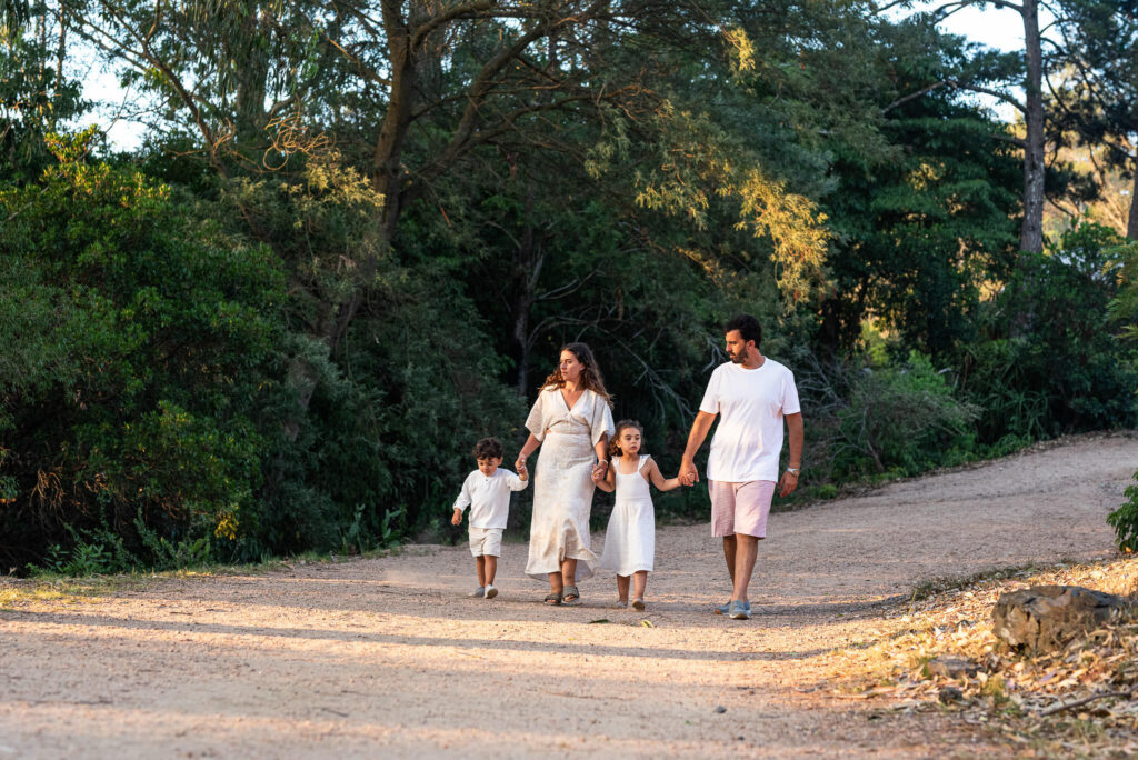 Família caminhando com os filhos por uma estrada de terra entre árvores