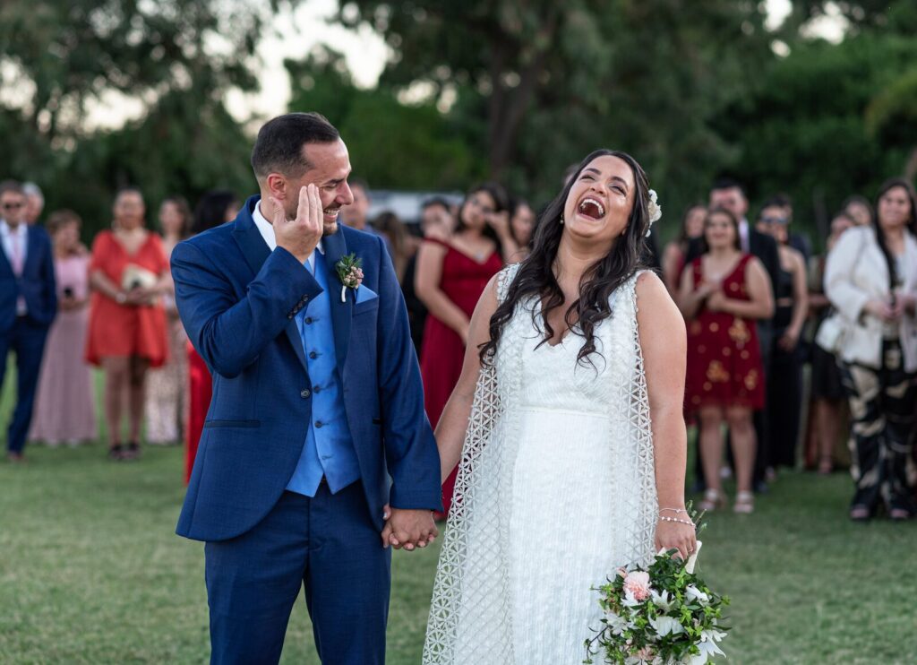 Los novios riéndose de la mano frente a los invitados