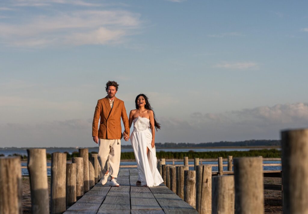 Casal caminhando por um píer de madeira ao entardecer