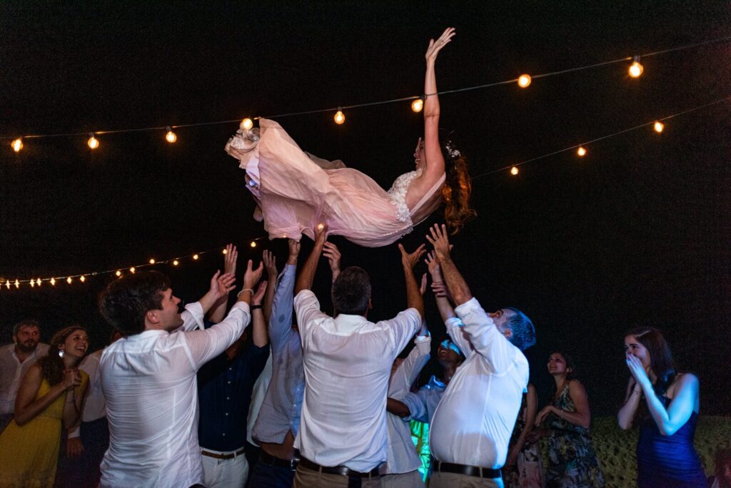 The bride lifted into the air at the party, under the lights