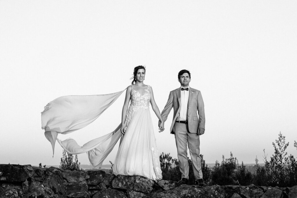 La novia y el novio de la mano con el velo al viento, en blanco y negro